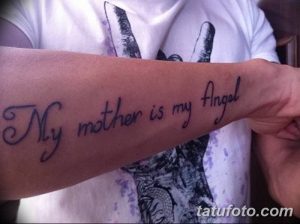 Фото татуировки на предплечье с надписью 'My mother is my Angel'. Изящный шрифт, выполненный синими чернилами.