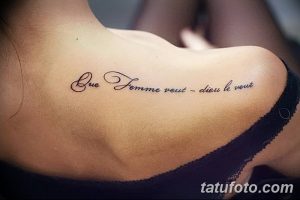 Фото татуировки надписью "Que Femme veut - dieu le veut" на плече. Элегантный шрифт и французский шарм.