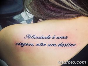 Фото татуировки надписью "Felicidade é uma viagem, não um destino" на плече. Красивый шрифт и вдохновляющий смысл.