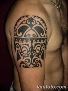 Фото тату: татуировка в стиле маори на плече. Черный рисунок с детализированными спиральными узорами и геометрическими фигурами.