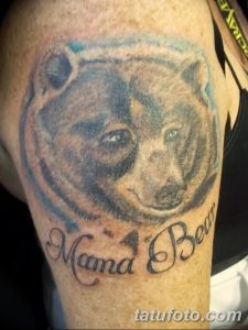 Фото тату медведя на плече с надписью "Mama Bear". Рисунок выполнен в реалистичном стиле с использованием серых и коричневых оттенков. Трогательный эскиз тату.