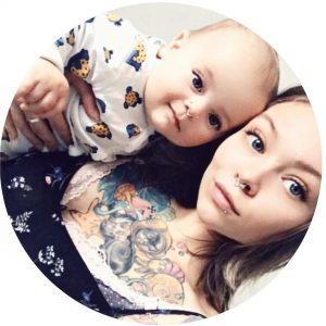 Фотография мамы с ребенком на руках, у которой видны татуировки на шее и руках.