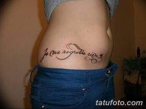 Фото тату на талии: надпись 'Je ne regrette rien' (Я ни о чем не жалею) выполненная элегантным шрифтом, минималистичный стиль.