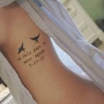 Фото тату на ребрах: маленькая черная птичка и надпись 'we only part to meet again 5-17-12', выполненные в минималистичном стиле.