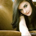 Фото девушки с татуировкой на руке, выполненной в стиле акварель. Рисунок татуировки изображает абстрактные узоры и цветочные мотивы.