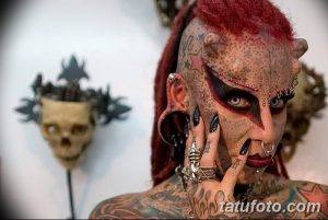 Фото тату: мужчина с экстремальными модификациями тела, включая татуировки на лице, пирсинг и импланты, демонстрирует уникальный стиль.