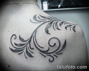 Фото тату: черная татуировка в технике дотворк, изображающая растительный орнамент на плече. Минималистичный и стильный дизайн.