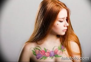 Фото тату: девушка с нежной татуировкой в виде букета тюльпанов на груди, выполненной в акварельном стиле.