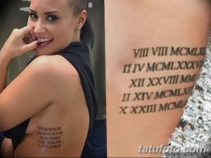 Фото тату: римские цифры на боку женщины, выполненные черными чернилами. Эскиз татуировки выглядит как последовательность дат, расположенных вертикально.