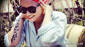 Фото тату на руке Деми Ловато. Изображение летящих птиц и надписи "faith". Черно-белый эскиз татуировки, символизирующий свободу и веру.