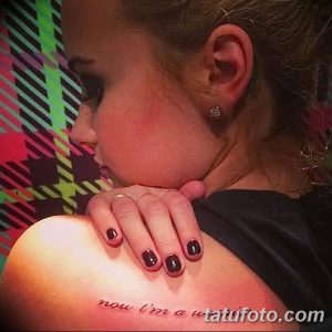 Фото тату надписи "now I'm a" на плече Деми Ловато. Простая, черно-белая татуировка, выполненная тонким шрифтом. Небольшой эскиз тату для девушек.