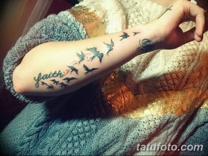Фотография татуировки с надписью 'Faith' и изображением летящих птиц на руке женщины.
