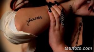Фотография татуировки с надписью 'Faith' на плече женщины, выполненной черными чернилами.