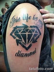 Фото тату бриллианта на плече с надписью 'This life is my diamond'. Черно-белый рисунок татуировки в реалистичном стиле.