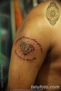 Фото татуировки на плече: цитата "Shine On, Dear Me" в круге с изображением символа. Оригинальный и вдохновляющий рисунок татуировки.
