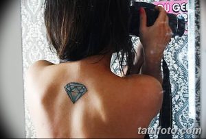 Фото тату голубого бриллианта на женской спине. Простой и элегантный рисунок татуировки с четкими линиями и гранями.