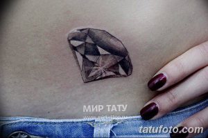 Фото тату маленького черного бриллианта на животе девушки. Изящный и минималистичный рисунок татуировки.