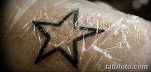 Фото свежей татуировки в виде звезды, покрытой прозрачной защитной пленкой. Видны контуры рисунка и покрасневшая кожа.