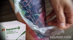 Фото процесса снятия защитной повязки с новой татуировки. Видна свежая, покрасневшая кожа с ярким рисунком.