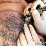 Фото процесса нанесения татуировки. Мастер в перчатках работает тату-машинкой над рисунком на теле клиента.
