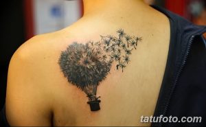 Фото тату одуванчика, стилизованного под воздушный шар, на спине. Семена одуванчика изображены в виде летящих облаков.