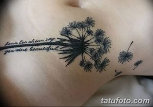 Фото тату одуванчика с цитатой на груди. Черно-белый рисунок с детальной проработкой одуванчика и красивой каллиграфией.