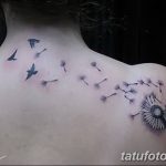 Фото минималистичной татуировки одуванчика с летящими птицами на спине. Черно-белый рисунок, выполненный тонкими линиями.