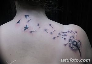 Фото минималистичной татуировки одуванчика с летящими птицами на спине. Черно-белый рисунок, выполненный тонкими линиями.
