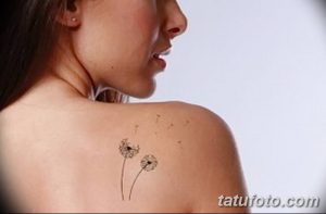 Фотография татуировки одуванчика с улетающими пушинками, расположенной на плече. Изображение выполнено в черно-серых тонах, с акцентом на детализацию.