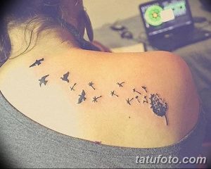 Фото татуировки одуванчика с летящими птицами, выполненной в минималистичном стиле на спине девушки, с акцентом на легкость и свободу.