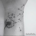Фото тату одуванчика на руке. Небольшой черно-серый рисунок с летящими семенами, выполненный в минималистичном стиле. Элегантный эскиз тату для девушек.