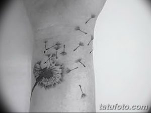 Фото тату одуванчика на руке. Небольшой черно-серый рисунок с летящими семенами, выполненный в минималистичном стиле. Элегантный эскиз тату для девушек.