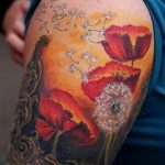 Цветная татуировка с изображением одуванчика и маков на руке. Рисунок выполнен в акварельной технике с использованием ярких красных и желтых оттенков.