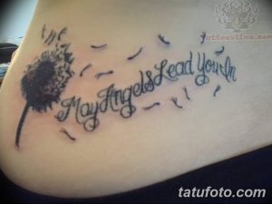 Татуировка одуванчика с летящими семенами и надписью "May Angels Lead You In" на боку. Изображение выполнено в черном цвете.