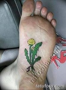 Фото цветной татуировки одуванчика на стопе. Желтая головка цветка и зеленые листья создают яркий и позитивный рисунок. Небольшой эскиз тату.