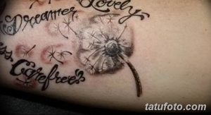 Фото тату одуванчика на руке с разлетающимися парашютиками и надписями 'Dreamer', 'Lovely', 'Carefree'. Черно-серый рисунок татуировки.
