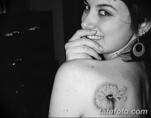 Фото тату одуванчика с птицей на плече. Черно-белый рисунок татуировки выполнен в реалистичном стиле.