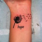 Фото тату одуванчика с надписью 'hope' на запястье. Черно-белый рисунок татуировки выполнен в минималистичном стиле.