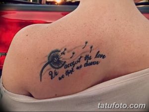 Фото тату одуванчика с надписью "We accept the love we think we deserve" на плече. Черно-белый рисунок татуировки выполнен в минималистичном стиле.