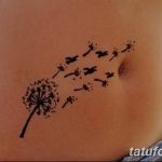 Фото тату одуванчика с разлетающимися семенами, расположенного на животе. Минималистичный дизайн, выполненный в черном цвете, подчеркивает изящество рисунка.