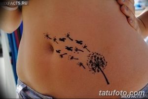 Фото татуировки на животе с изображением одуванчика, из которого вылетают птицы, выполненное тонкими черными линиями.