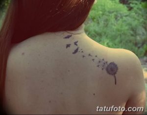 Фото татуировки на шее с изображением одуванчика, из которого вылетают птицы, выполненное тонкими черными линиями.