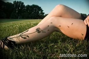 Фото тату одуванчика на ноге, с летящими семенами. Черно-белый рисунок татуировки, выполненный в реалистичном стиле, подчеркивает красоту природы.