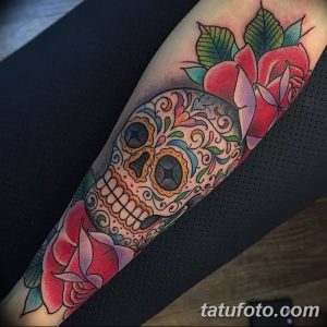 Фото тату: красочный рисунок черепа в стиле сахарной черепушки (calavera) с розами на предплечье. Веселый и жизнерадостный дизайн.