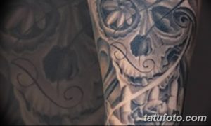 Фото тату черепа, окруженного розами в стиле blackwork. Черно-белый рисунок татуировки на руке с использованием плотных черных линий.