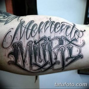 Черно-белое фото татуировки с надписью 'Morrerdo Mil' на предплечье. Изящный шрифт, детализированные линии и тени.