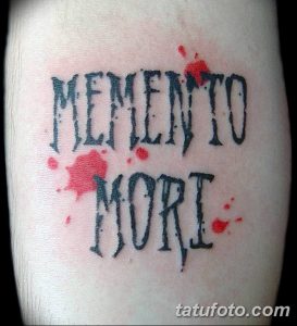 Фото татуировки на руке с надписью 'Memento Mori', выполненной в стиле граффити с добавлением красных брызг краски. Необычный и яркий рисунок.