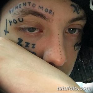 Фото тату надписи 'Memento Mori' и других символов на лице. Необычный и провокационный дизайн.