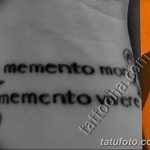 Фото тату с повторяющейся надписью 'Memento Mori' на руке. Минималистичный, черно-белый рисунок татуировки.