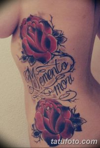 Фото тату с красными розами и надписью 'Memento Mori' на боку. Красивый, детализированный рисунок татуировки.